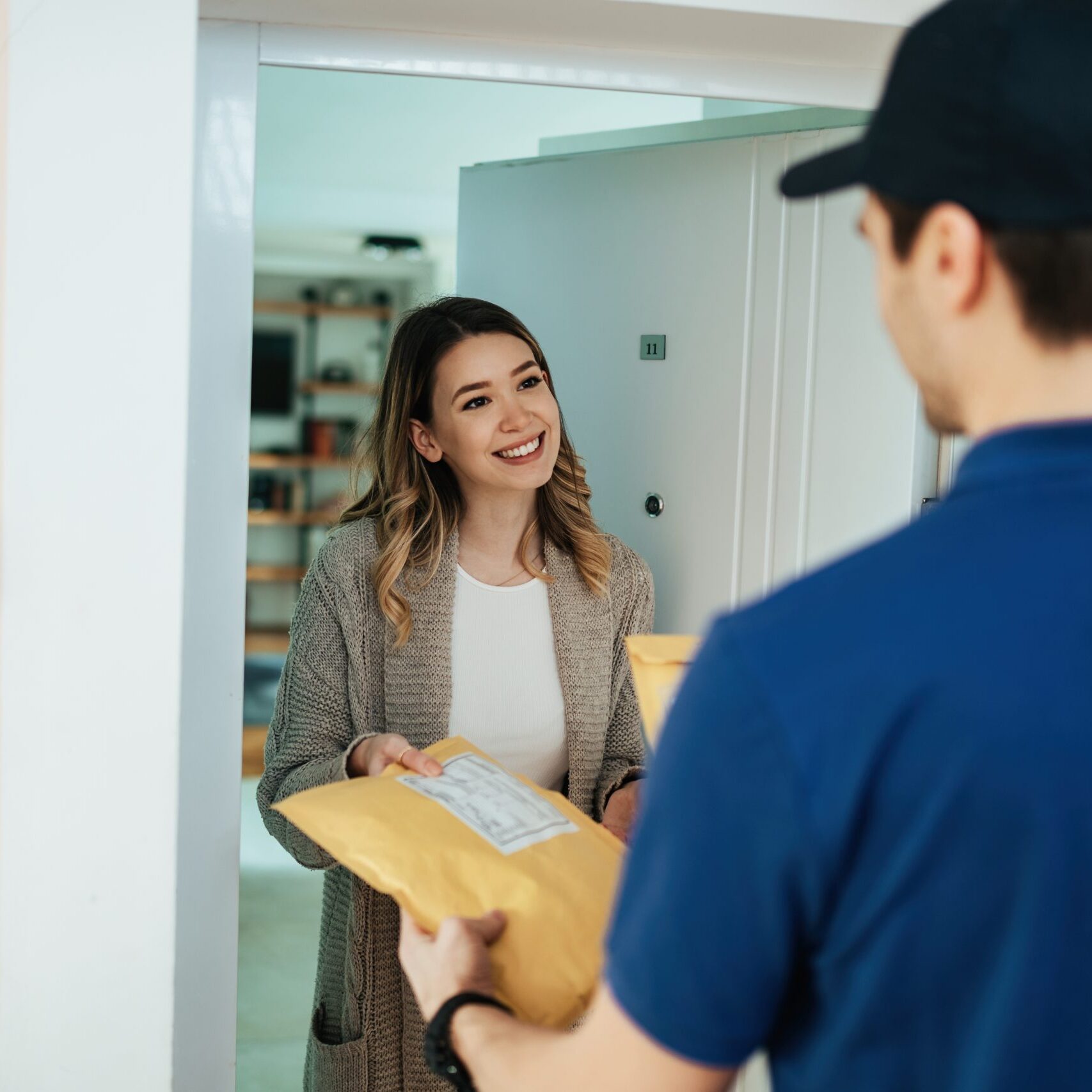 Happy woman taking package from a courier while receiving home delivery.